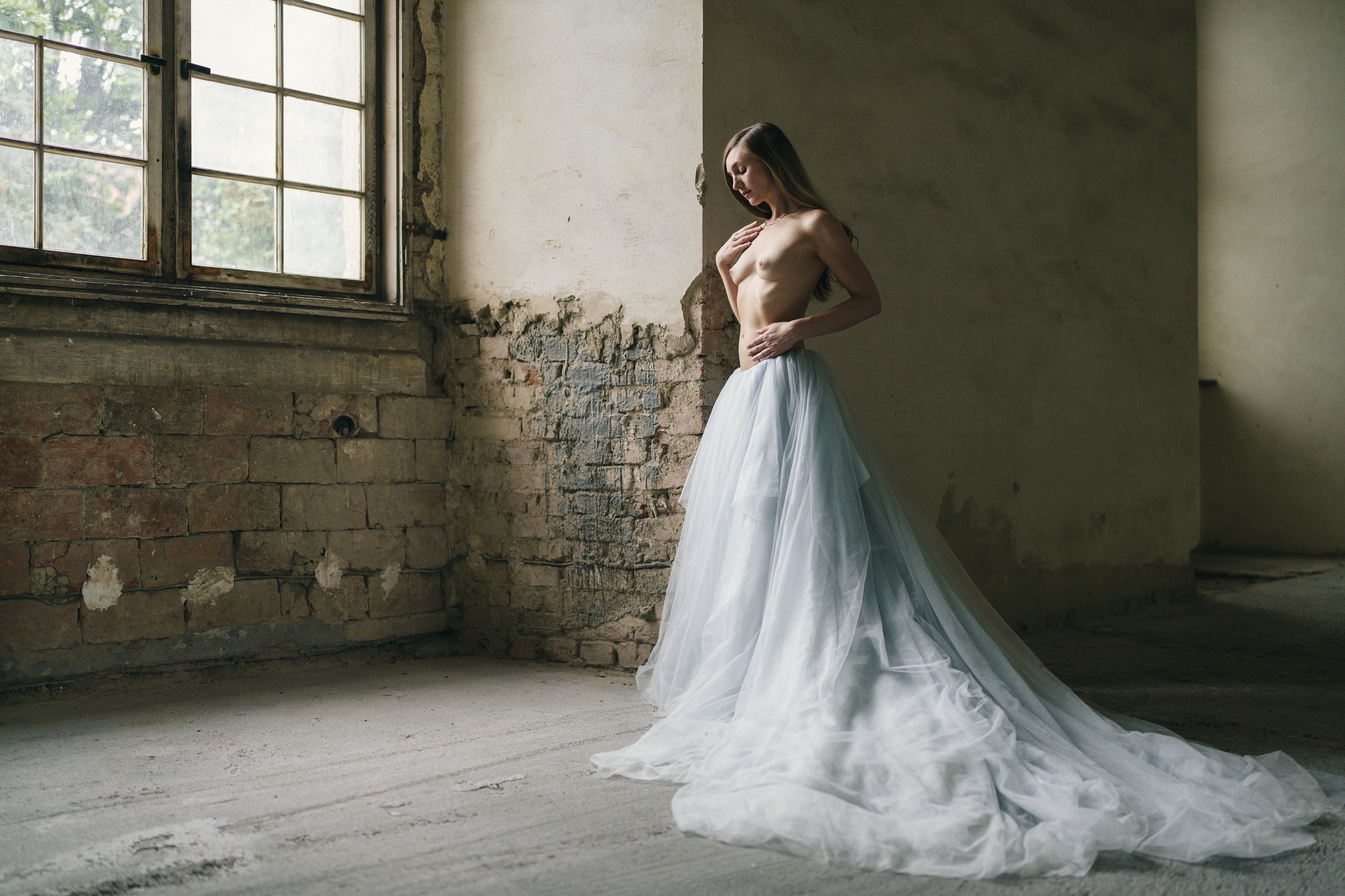 abandoned space, artistic nude, ball gown, classical elegance, delicate grace, dreaminess, elegant pose, indoors, minimalist aesthetic, natural beauty, neoclassical influence, one person, poetic sensuality, side view, standing, window, young woman, Alex Tsarfin