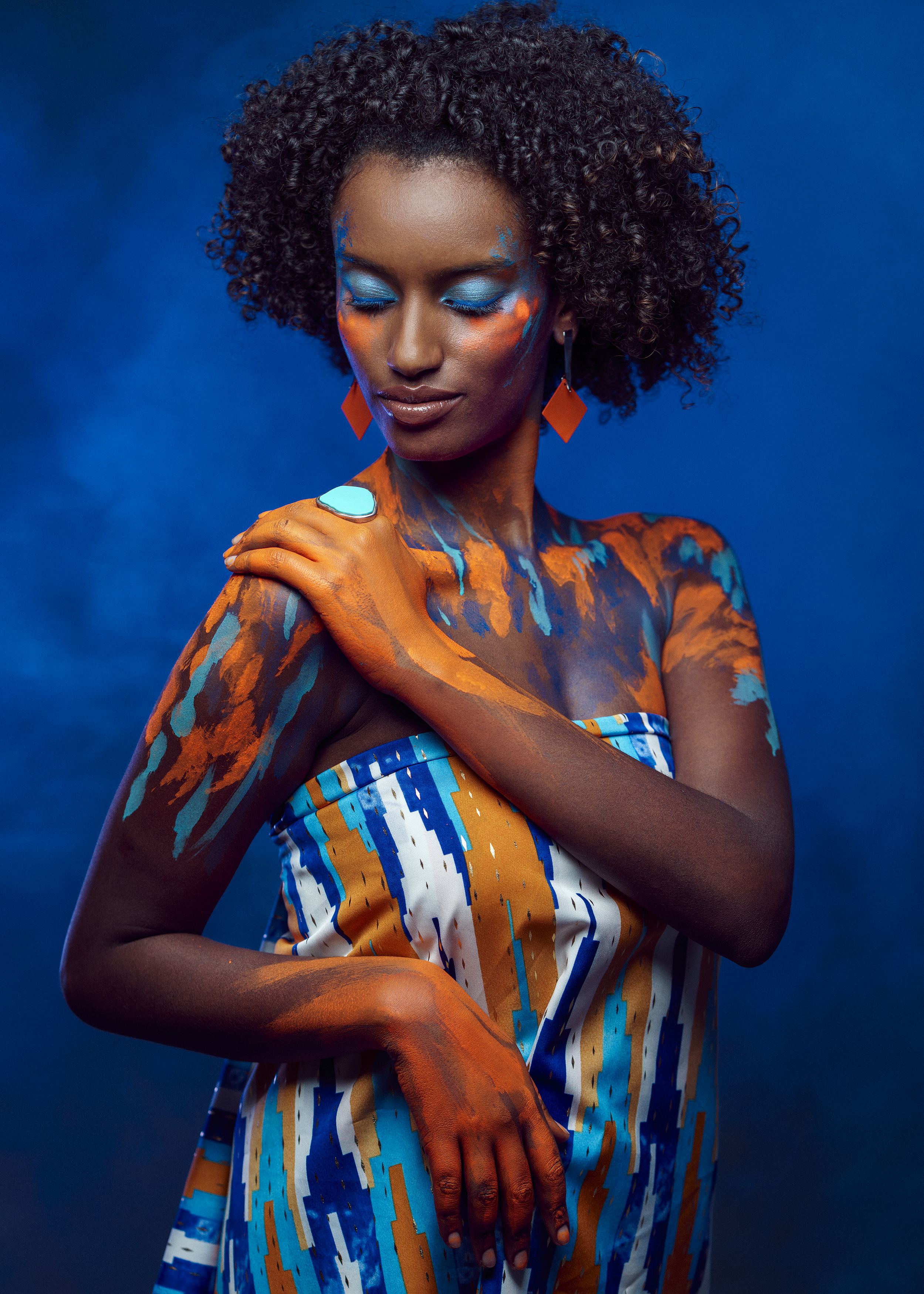 african beauty, amber accents, artistic portrait, body art, creative makeup, curly hair, dark skin, delicate pose, earrings, ethnic style, exotic elegance, female portrait, front view, painted body, shoulder touch, smoke, vibrant colors, young woman, Alex Tsarfin