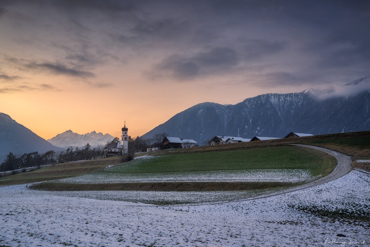 acres, agicutural building, agriculture, alps, austria, austrian alps, bend, bending road, church, clouds, evening, evening glow, farmhouse, fog, foggy, forest, gravel road, hey barn, hill, hills, houses, landscape, meadows, mieming, mieminger plateau, mo, Ludwig Riml
