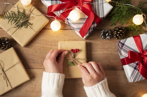 Woman's hands tying the bow on vintage present on rustic background. 